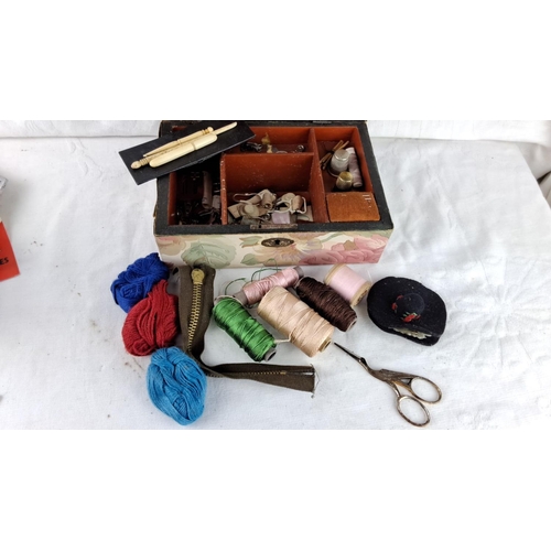 87 - Vintage sewing box with floral design, containing various threads, zippers, thimbles, and scissors.