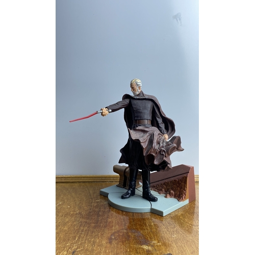 282 - Collectible action figure, depicting a character with a red lightsaber, mounted on a base.