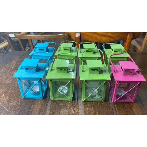 303 - Set of eight vibrant metal lanterns in blue, green, and pink. Each features glass panels and metal c... 