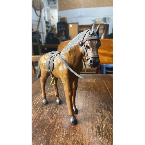 324 - Hand-carved wooden horse figure with leather saddle and bridle detailing.