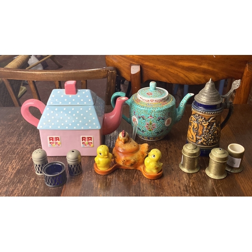 329 - Collection of decorative teapots, salt shakers, and figurines. Includes a house-shaped pastel teapot... 