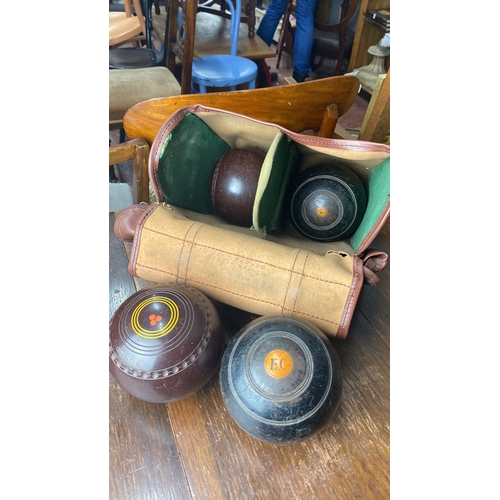 336 - Set of four vintage lawn bowls with carrying case, featuring distinctive markings and classic leathe... 