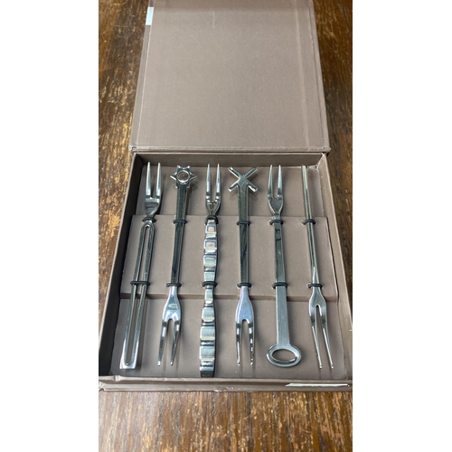 343 - Sambonet boxed cutlery set featuring seven stainless steel cocktail forks, each with unique designs.... 