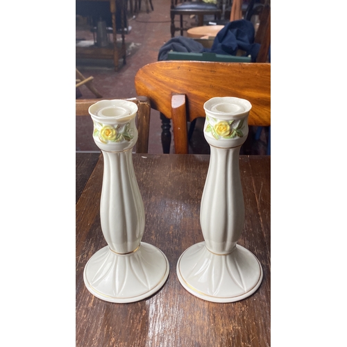 348 - Pair of Belleek candlesticks with delicate floral motifs and gold accents.