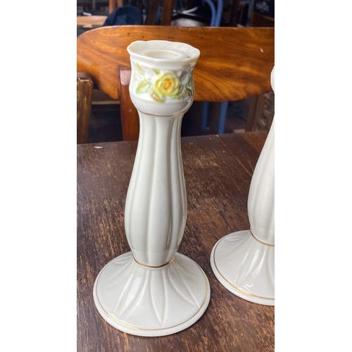 348 - Pair of Belleek candlesticks with delicate floral motifs and gold accents.