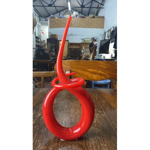 356 - Red glass sculpture featuring an abstract spiral design with a glossy finish.