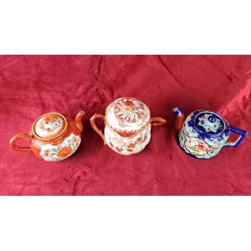 103 - Set of three Japanese teapots with vibrant hand-painted floral and figural designs, including two wi... 