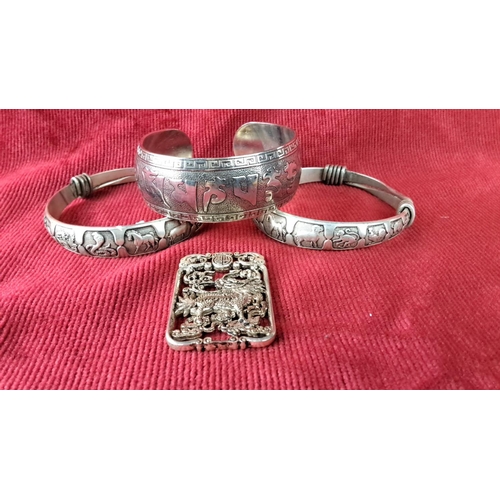 116 - Set of three intricately engraved white metal bangles with cultural motifs, paired with an ornate re... 