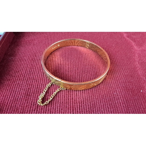 128 - Gold-plated hinged bangle with etched design, safety chain, marked 