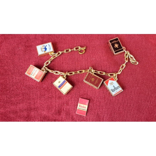 129 - Gold-tone charm bracelet featuring miniature cigarette pack charms: Camel, Winston, Marlboro, Muratt... 