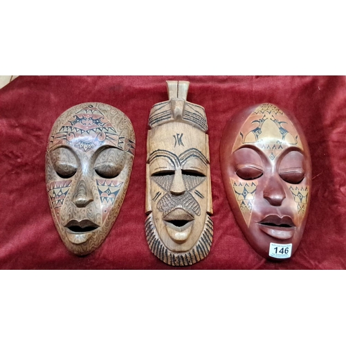 146 - Hand-carved tribal masks, set of three, feature intricate geometric patterns and are crafted from na... 