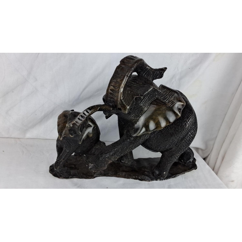 166 - Large elephant sculpture depicts a parent and child with intricate detailing and rich, dark hues.