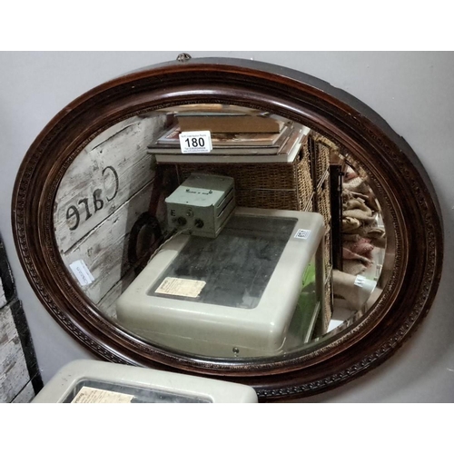 180 - Antique oval wall mirror with carved dark wood frame features intricate beaded detailing.