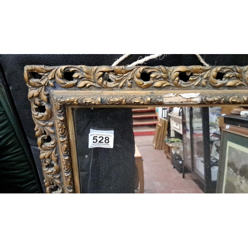 528 - Ornate vintage mirror with a carved gilt frame featuring scrolling leaf patterns, from the Victorian... 