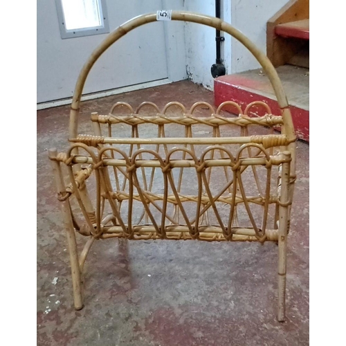 535 - Mid-century modern rattan magazine rack features a natural woven design and curved handle.