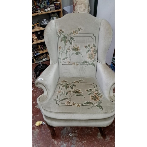 536 - Upholstered wingback chair with floral embroidery and wooden cabriole legs, in a classic Victorian s... 