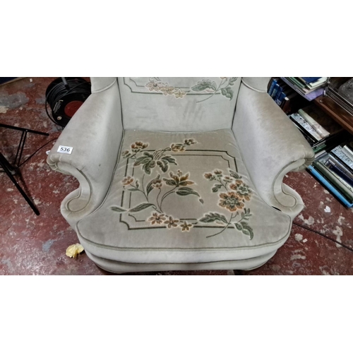 536 - Upholstered wingback chair with floral embroidery and wooden cabriole legs, in a classic Victorian s... 