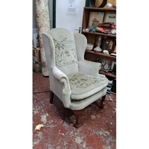 536 - Upholstered wingback chair with floral embroidery and wooden cabriole legs, in a classic Victorian s... 