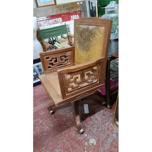 546 - Decorative Oak swivel chair featuring intricate lattice armrests and upholstered backrest.