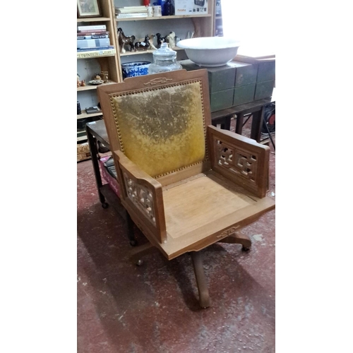 546 - Decorative Oak swivel chair featuring intricate lattice armrests and upholstered backrest.