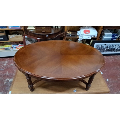 553 - Round mahogany coffee table with carved, fluted legs, and a rich, warm finish.