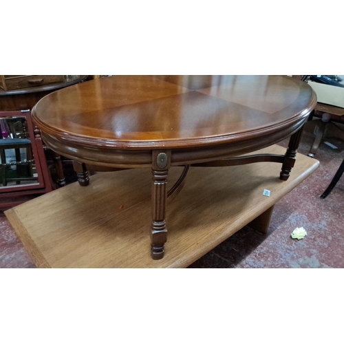 553 - Round mahogany coffee table with carved, fluted legs, and a rich, warm finish.