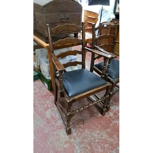 555 - Pair of wooden ladder-back armchairs with turned legs and black upholstered seats, rustic design.