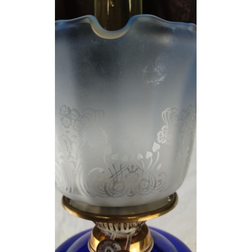 420 - Victorian brass oil lamp with ornate column base and cobalt blue glass font, featuring an etched gla... 