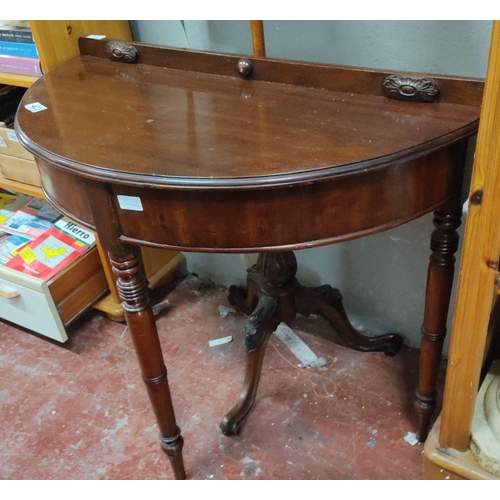 423 - Mahogany demi-lune side table with carved details and elegantly turned legs, featuring a central ped... 