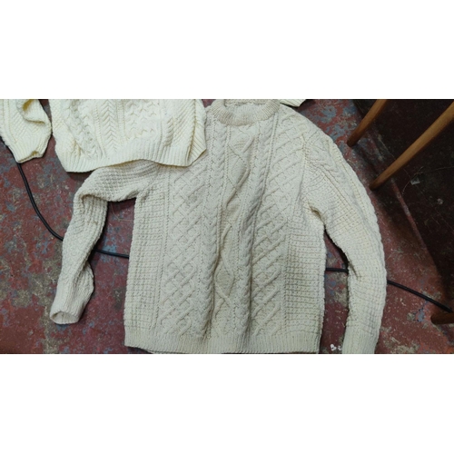 455 - Two cream Aran knit sweaters featuring traditional cable patterns, crafted from soft wool. Classic I... 