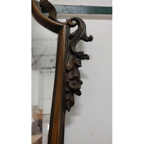 458 - Ornately carved wooden mirror with floral motifs,Victorian style. Features a decorative ribbon and s... 