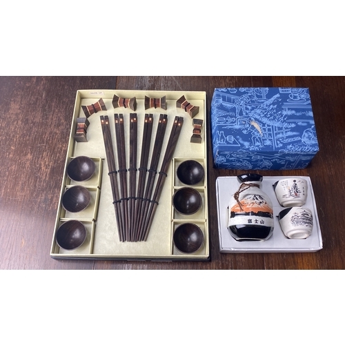 333 - Japanese dining set with wooden chopsticks, rests, and bowls. Includes sake bottle and cups with tra... 