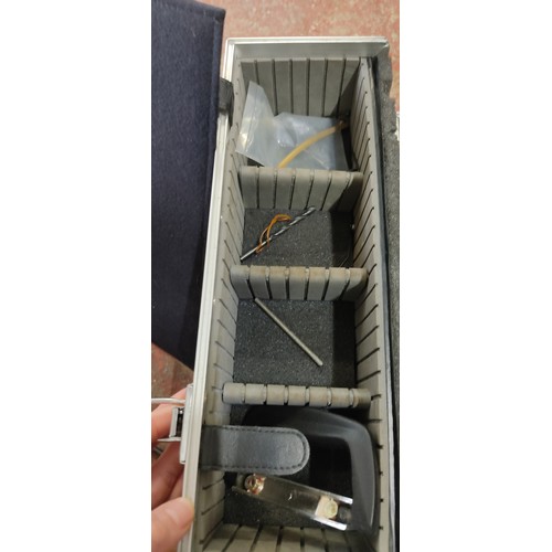 175 - Metal storage case with dual locks and foam interior, containing assorted tools and accessories.