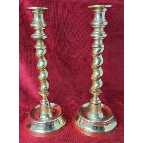 82 - A pair of vintage brass candlesticks with barley twist stems, each measuring 30cm tall.