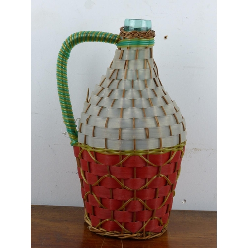 134 - A vintage jug with decoratively woven cover.