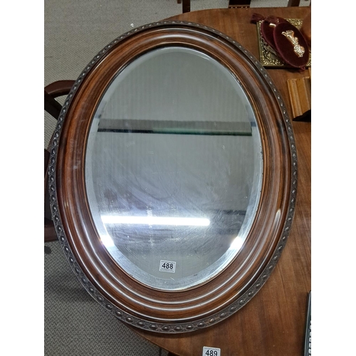 488 - An oval framed mirror with bevelled glass. Measuring 92x67cm.