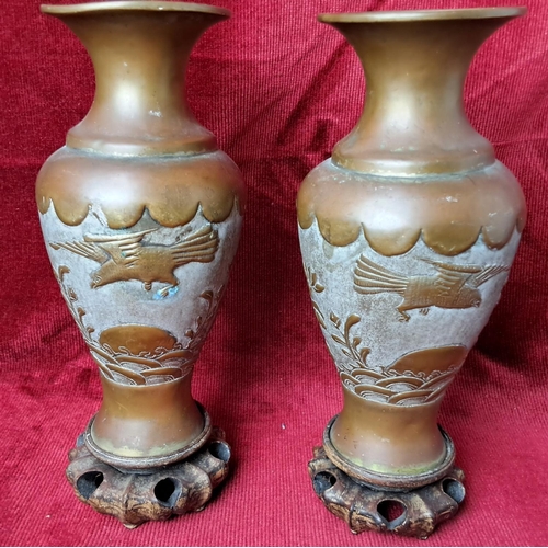 42 - A pair of vintage Chinese/ Japanese brass vases with wooden bases, each measuring 21cm tall.