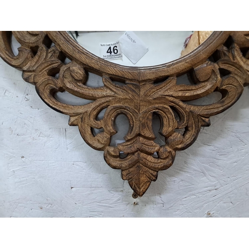 46 - A decorative wall mirror with highly carved wooden frame, measuring 65cm.