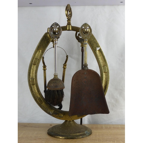 213 - A vintage brass fireside companion set, modelled as a horse shoe.