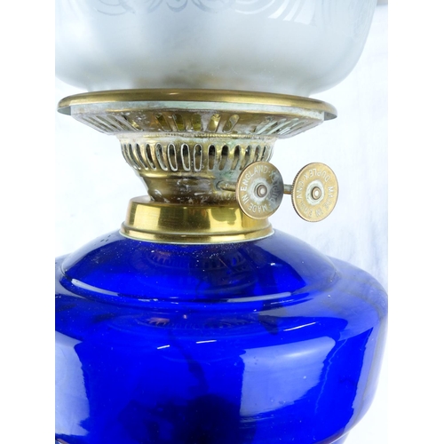 228 - Victorian brass oil lamp with ornate column base and cobalt blue glass font, featuring an etched gla... 