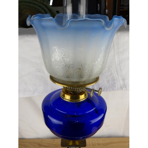 228 - Victorian brass oil lamp with ornate column base and cobalt blue glass font, featuring an etched gla... 