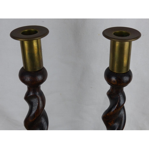 233 - A pair of antique wooden candlesticks with barley twist stems. Measuring 31cm tall.