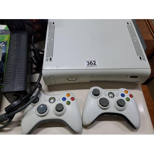 362 - An Xbox 360, two controllers and an assortment of games.