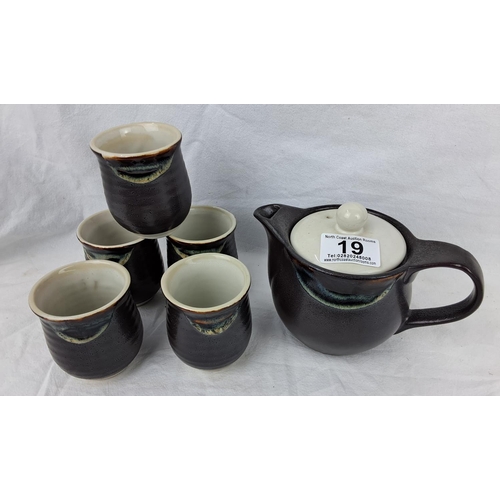 19 - A studio pottery tea pot and 5 matching cups.