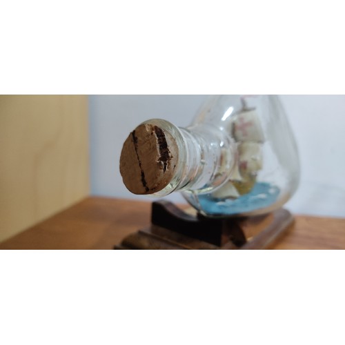 26 - A vintage ship in a bottle of the Mary Rose on wooden stand. Measuring approx 14cm in length.