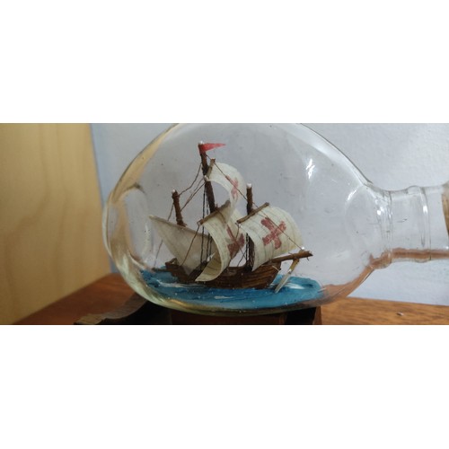 26 - A vintage ship in a bottle of the Mary Rose on wooden stand. Measuring approx 14cm in length.