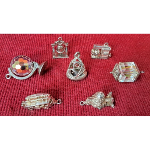 82 - A collection of 7 sterling silver and metal charms.