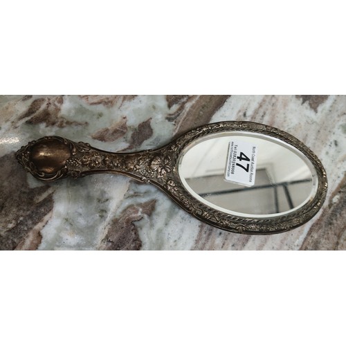 47 - An antique silver plated hand mirror. Measuring 26cm.