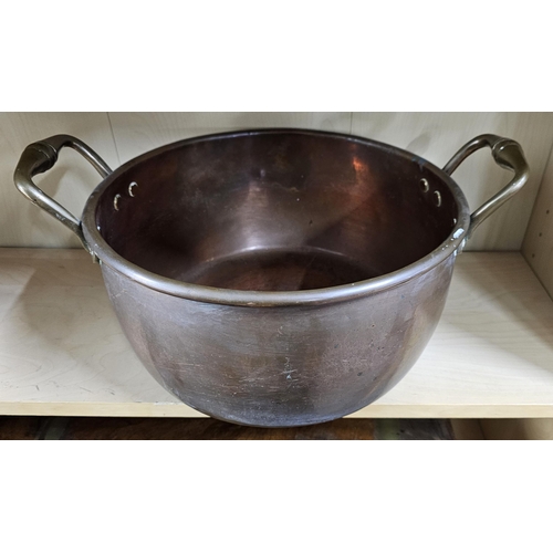 16 - A large antique copper pan with brass handles, measuring 33cm wide (excluding handles) & 16cm deep.