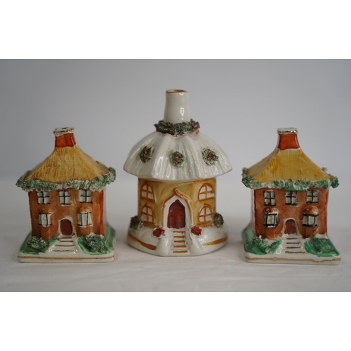 307 - Two Staffordshire pottery money boxes and another in the style of houses.